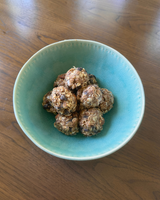 A bowl filled with Almond Butter Protein Balls, featuring oats, chocolate chips, and a crunchy texture. 
