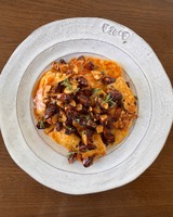  A plate of Hot Honey Halloumi topped with crunchy nuts and herbs, served on a white dish.