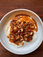 A bowl of creamy ricotta topped with caramelized almonds and drizzled with honey