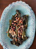  "A plate of roasted broccolini topped with almonds and grated cheese.