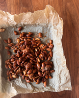 A batch of roasted almonds on crumpled parchment paper.