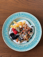 A yogurt bowl topped with fresh pineapple, berries, nuts, chia seeds, and a drizzle of honey.