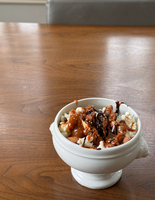  A caramel sundae topped with popcorn, almonds, and drizzled with chocolate.