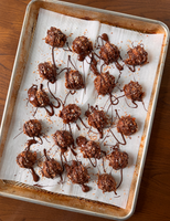  A baking sheet with no-bake samoas topped with toasted coconut and drizzled with melted chocolate.