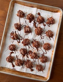  A baking sheet with no-bake samoas topped with toasted coconut and drizzled with melted chocolate.