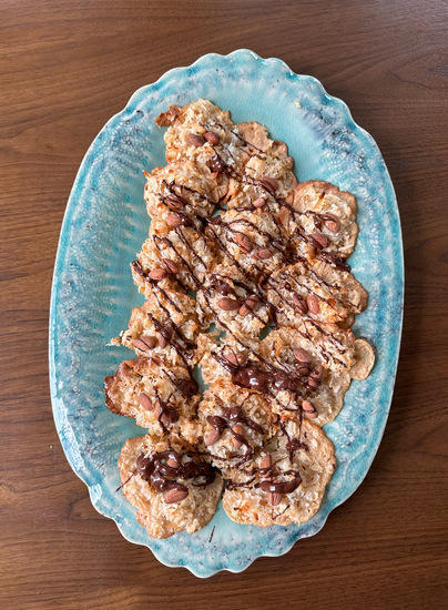 A plate of coconut macaroons topped with almonds and drizzled with chocolate.